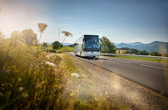 Autocar de tourisme sur une route de campagne bordée de fleurs, en direction du Sud de la France