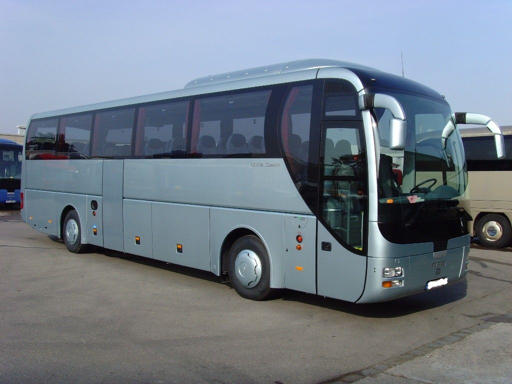 Autocar de grand tourisme gris circulant sur route, exemple de car adapté aux longs trajets