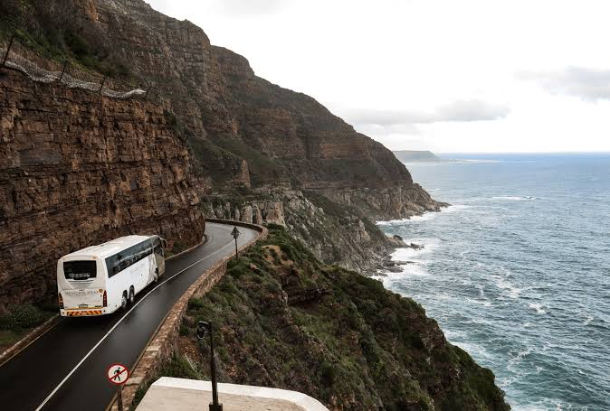Autocar circulant sur une route en corniche au-dessus de falaises et de la mer lors d'une excursion littorale