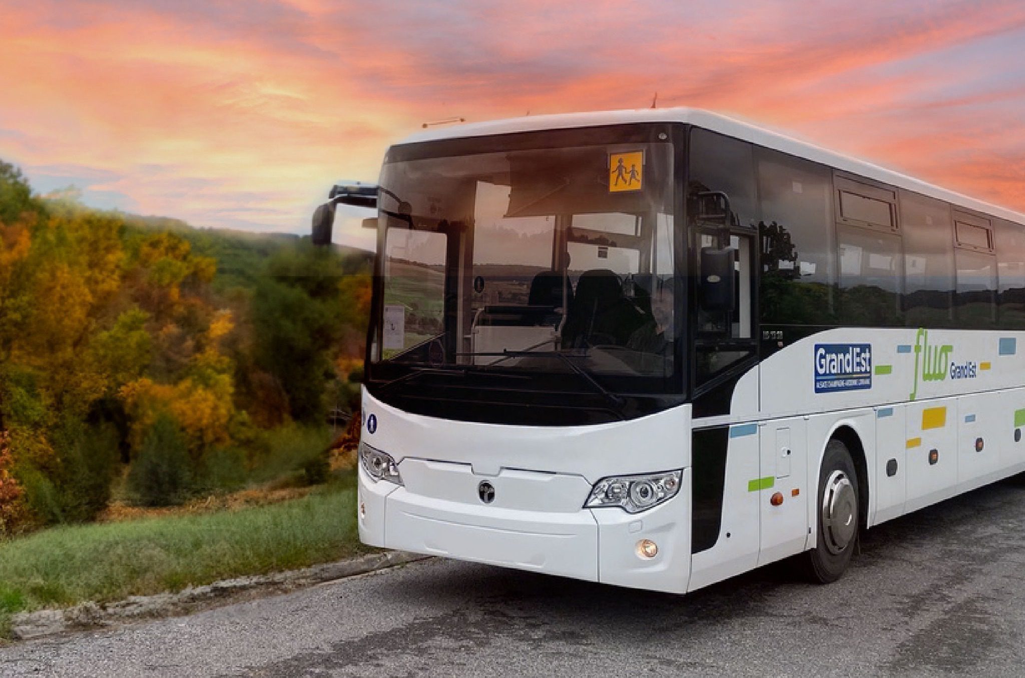 Bus scolaire régional circulant sur une route de campagne au coucher du soleil