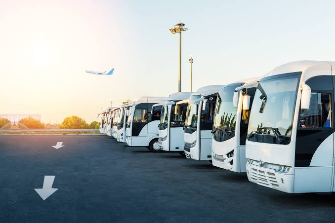 Flotte d'autocars garée à l'aéroport pour des transferts de groupe, illustrant l'usage du car pour les longues distances