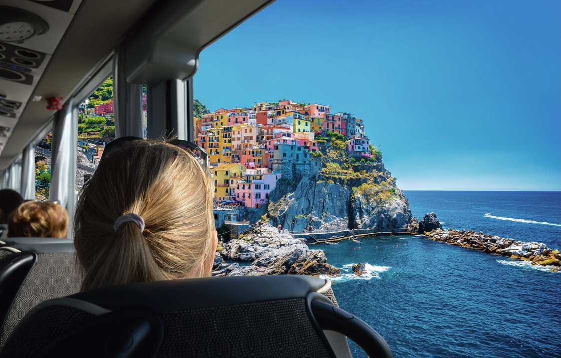 Passagère admirant un village côtier coloré depuis la fenêtre d'un autocar lors d'une journée à la mer