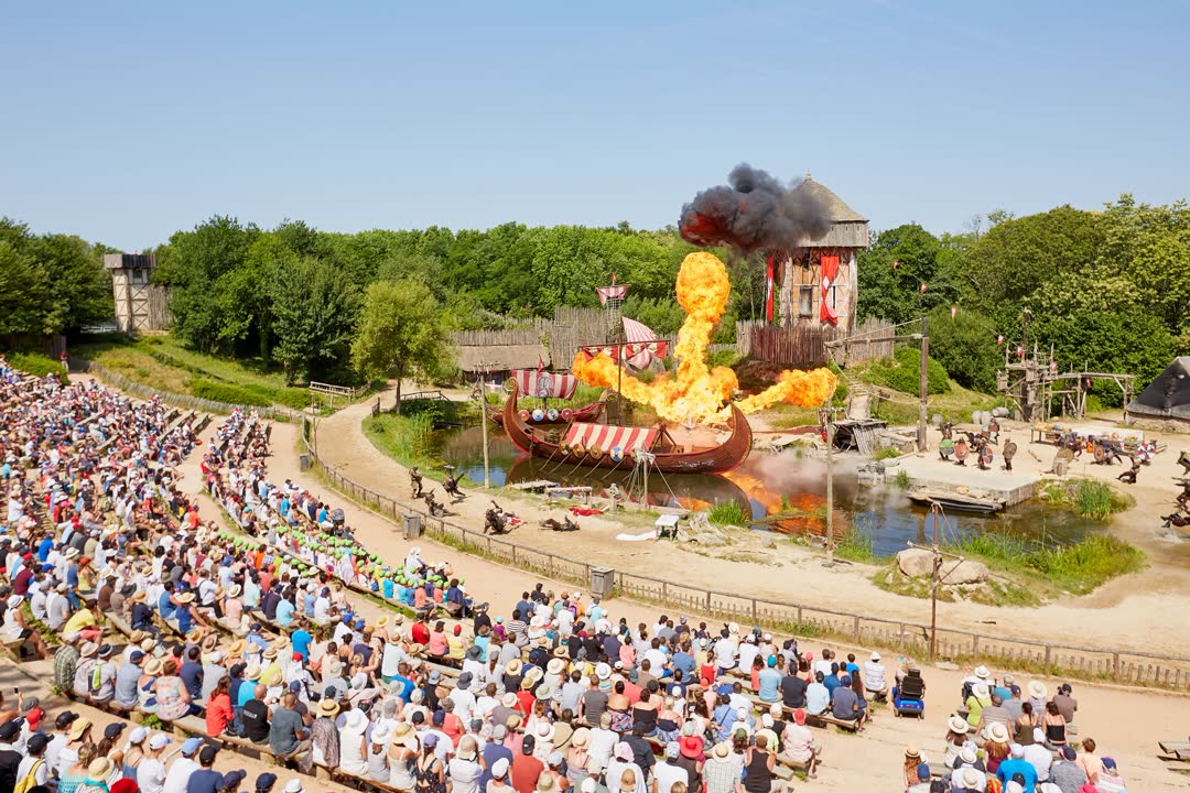 Foule de visiteurs assistant au spectacle des Vikings avec drakkars en flammes lors d'un voyage au Puy du Fou