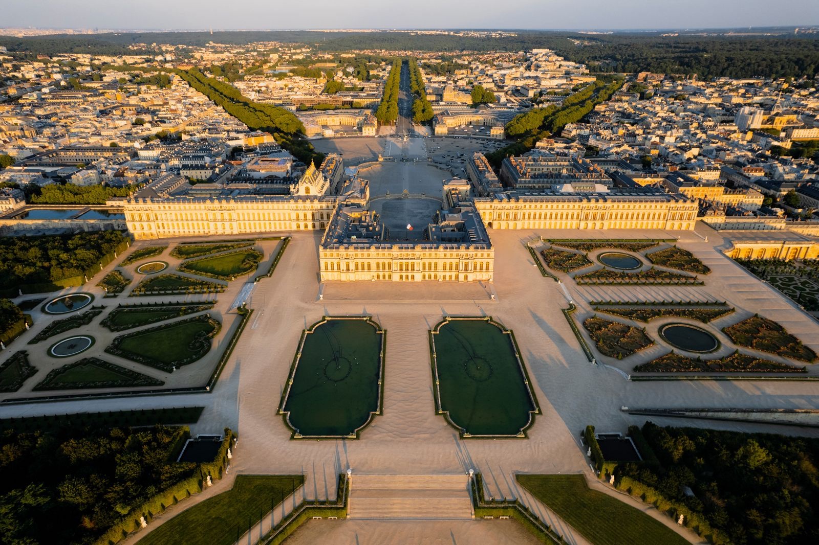 Vue aérienne du château de Versailles et de ses jardins à la française au coucher du soleil